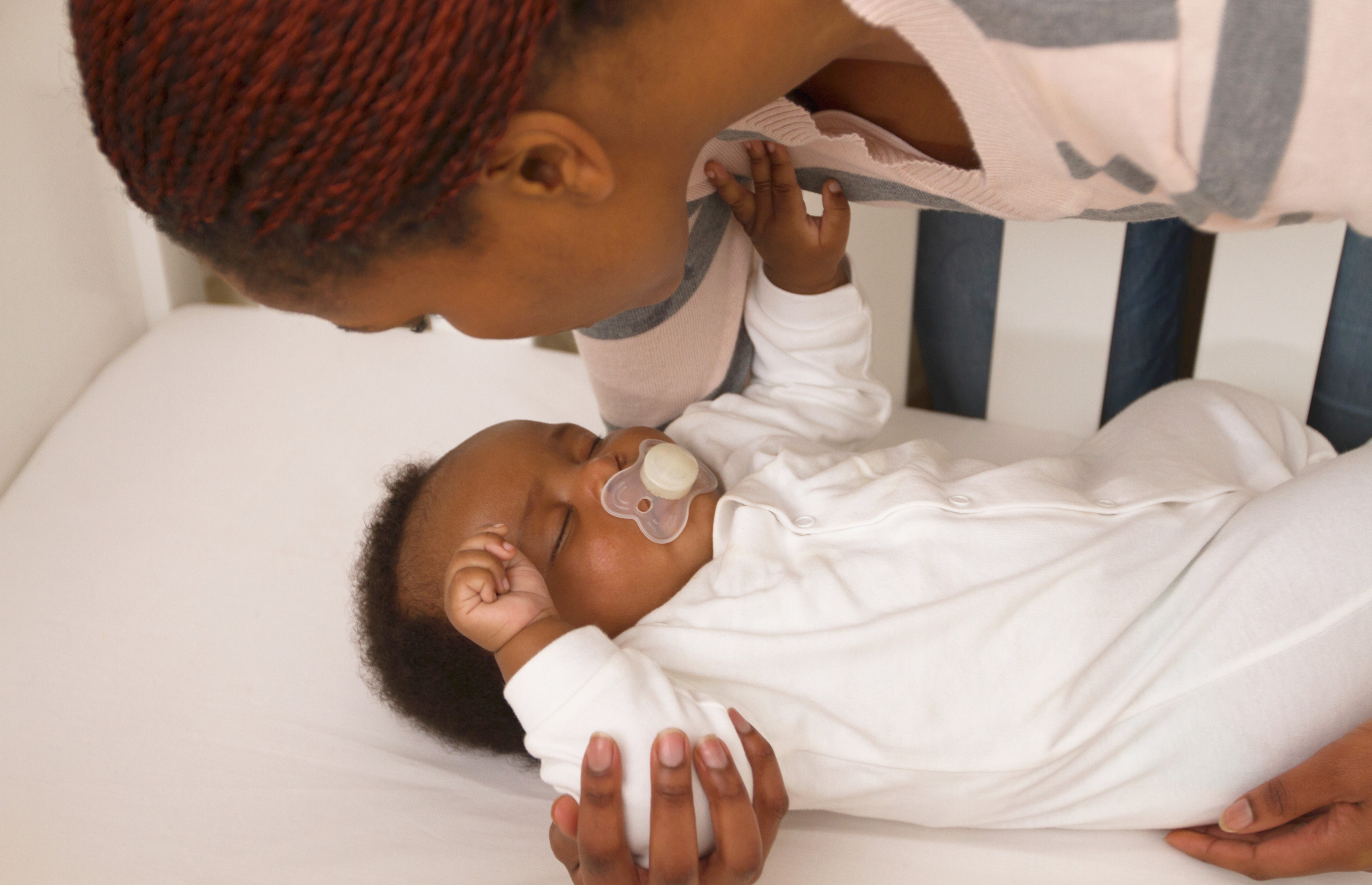 close-up-of-african-mother-putting-baby-down-in-crib-cape-town-south